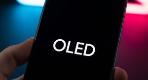 گوشی موبایل با نوشته OLED روی صفحه مشکی در دست یک نفر با پس‌زمینه نئونی